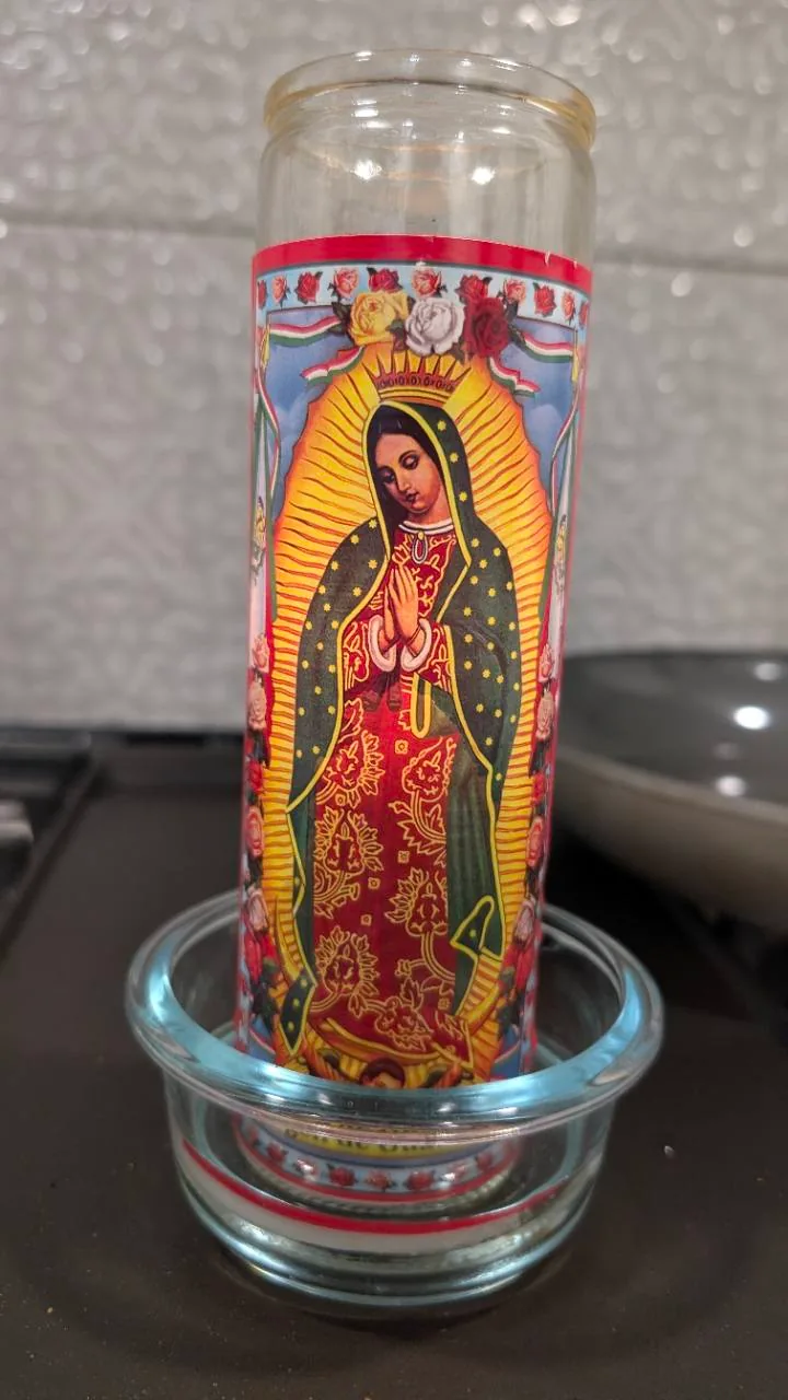 A Virgen de Guadalupe prayer candle in a glass holder