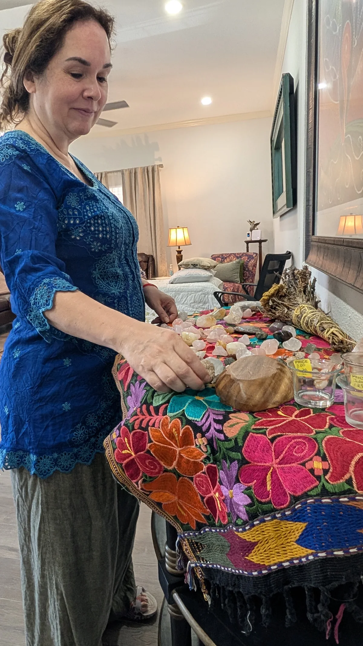 Sonia arranging crystals on an embroidered table at Madre Tierra