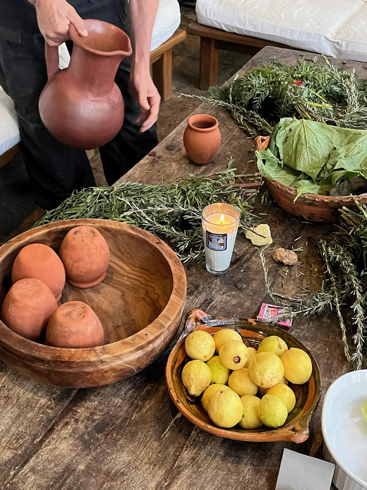 Herbs, fruit, a candle and clay pieces gathered on a wooden table in Mexico.